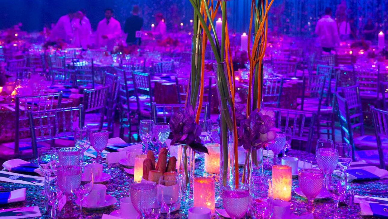 Elegant banquet table set for an event by a premier event planning company, with floral centerpiece and blue lighting.