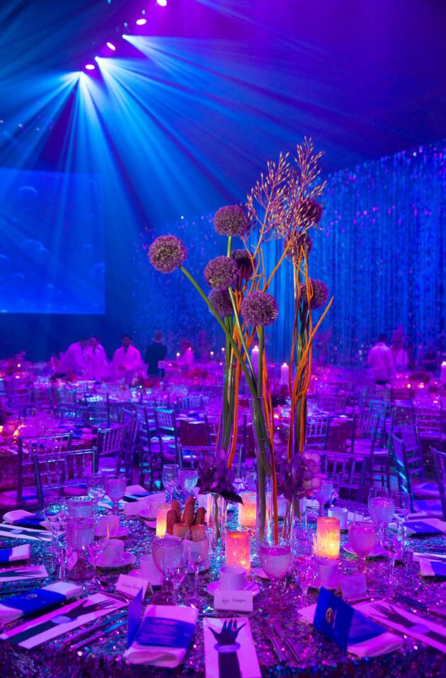 Elegant banquet table set for an event by a premier event planning company, with floral centerpiece and blue lighting.