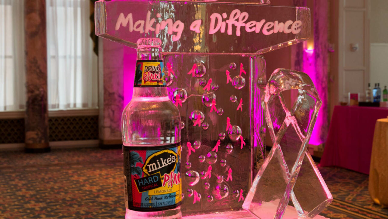 Display featuring mike's hard lemonade bottles, a tiered ice sculpture with brand signage, and ribbon decorations curated by an event planning company.