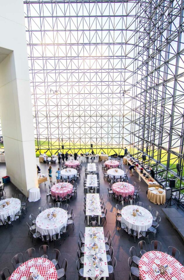 Banquet setup in a modern hall with large glass windows and geometric metal framework, designed by top event planners.