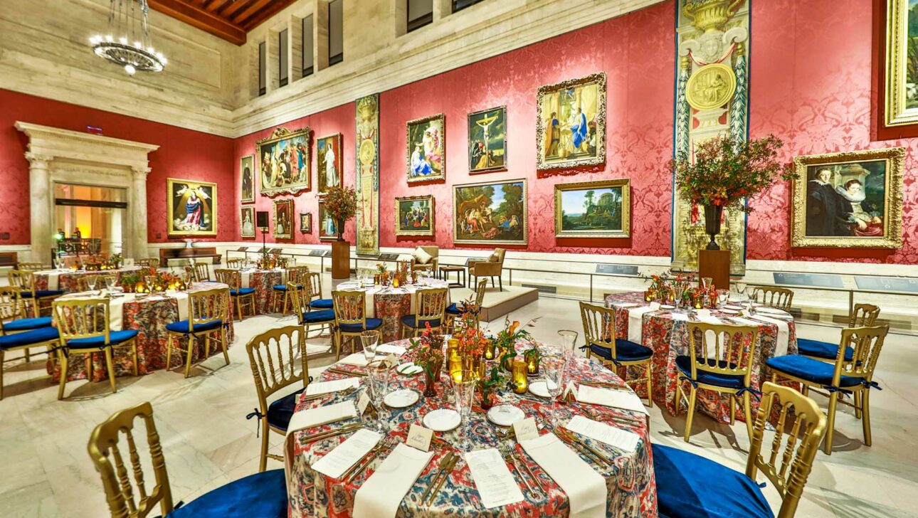 Elegant dining hall with tables set for a formal event, surrounded by ornate art and richly decorated walls, serving as an ideal event venue space.