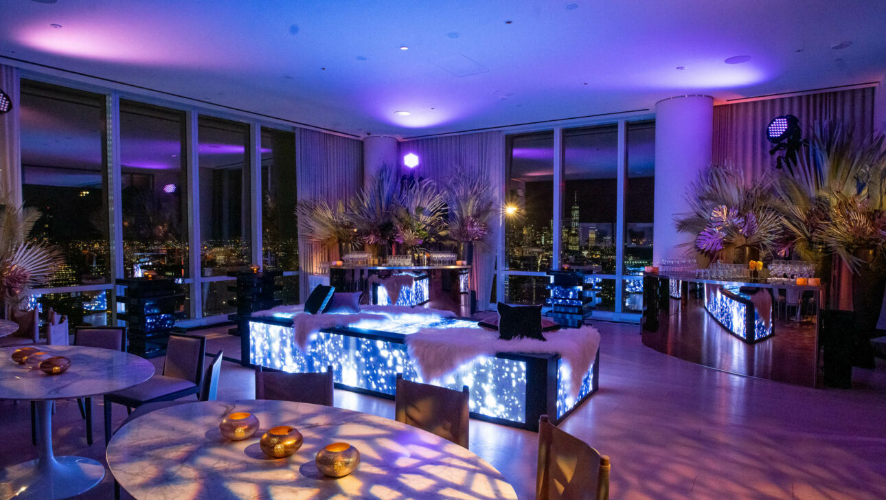 Chic event venue space with ambient lighting and cityscape views through floor-to-ceiling windows.
