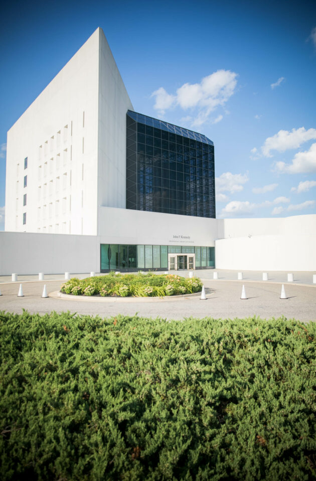 Modern event venue space with a large glass facade and white walls under a clear blue sky.