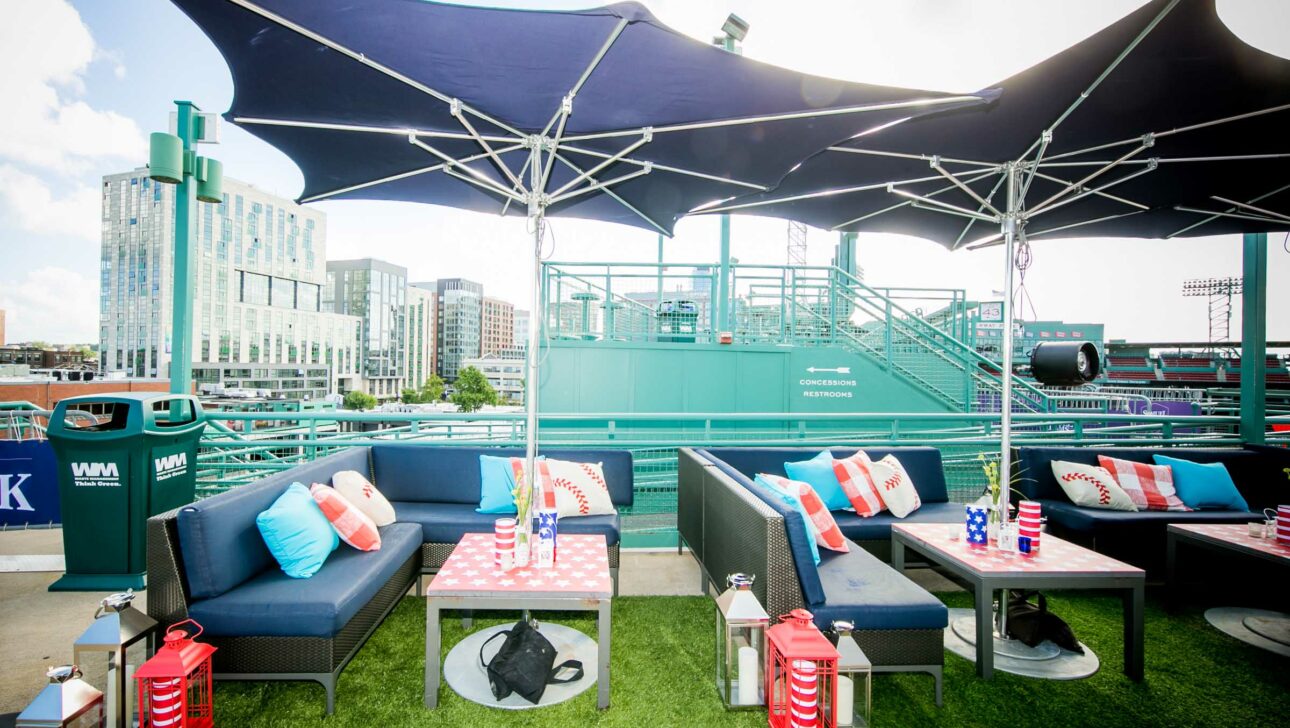 Outdoor lounge area with sofas and tables set up under canopy shades at a stadium managed by a top-tier event planning company.
