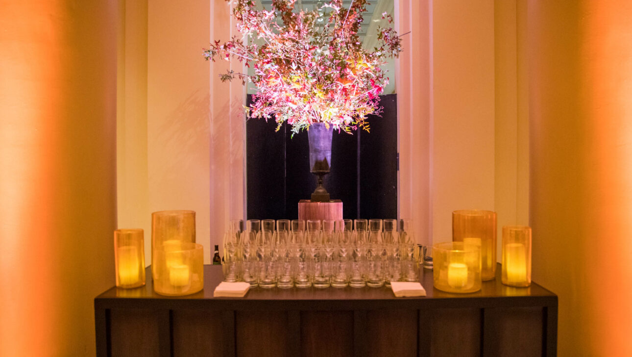 Elegant event planning company setting with a floral centerpiece, candlelit ambiance, and glasses arranged on a table.