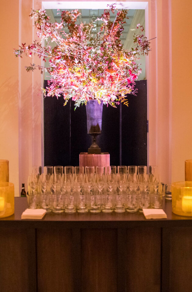 Elegant event planning company setting with a floral centerpiece, candlelit ambiance, and glasses arranged on a table.