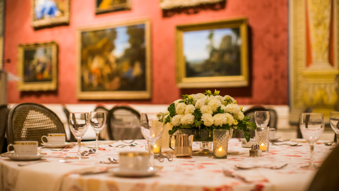 Elegant dining table set for a meal amidst an art-adorned gallery room within an event venue space.