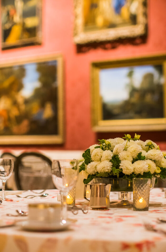 Elegant dining table set for a meal amidst an art-adorned gallery room within an event venue space.