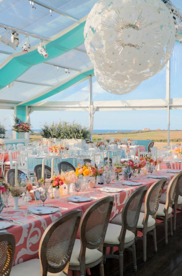Elegant outdoor event venue space setup with tables, floral centerpieces, and a view of the countryside.