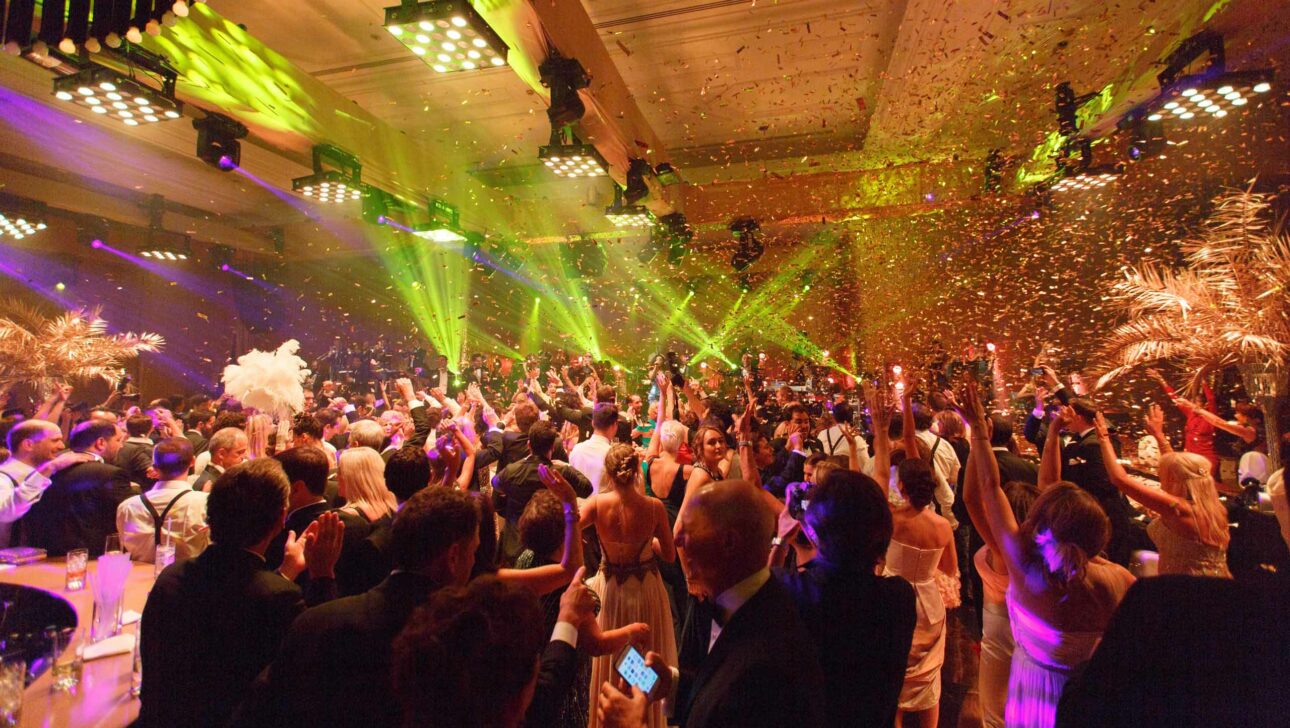 An event planning company hosted a lively indoor celebration with guests dancing under vibrant lights and confetti.