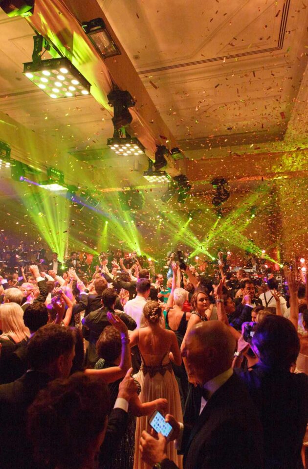 An event planning company hosted a lively indoor celebration with guests dancing under vibrant lights and confetti.