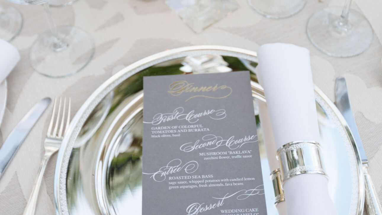 Elegant table setting for a formal event planned by an event planning company, with menu cards, silverware, and floral centerpiece.
