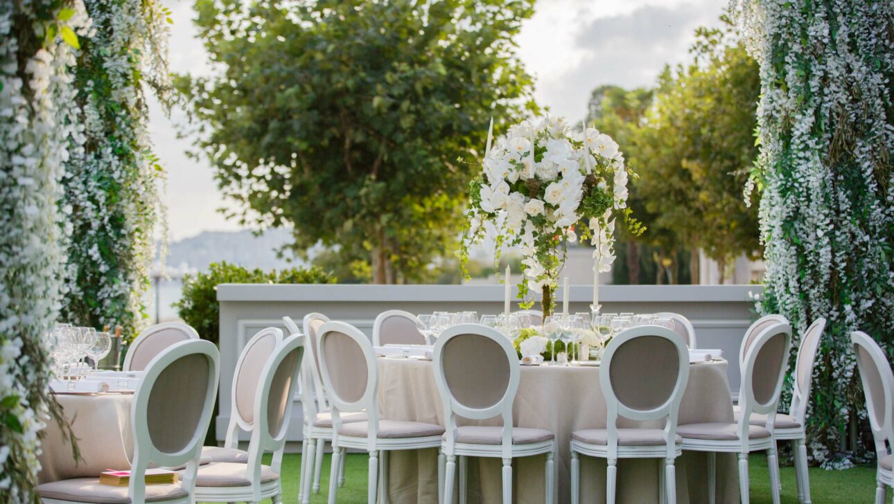Elegant outdoor wedding reception setup by event planners with white floral decorations and seating.