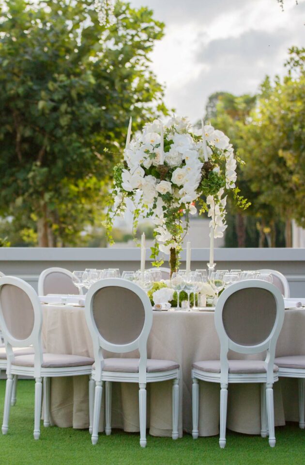 Elegant outdoor wedding reception setup by event planners with white floral decorations and seating.