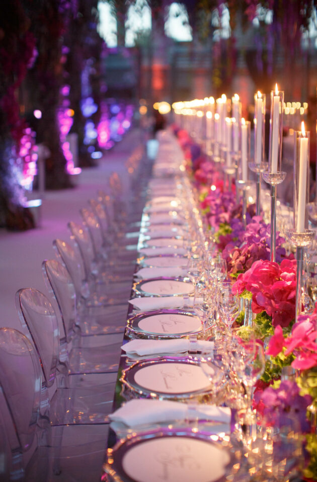 An elegantly set banquet table with tall candles and pink floral arrangements, meticulously arranged by a premier event planning company.